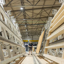 Produktionsbereich mit aufgestellten Holzbauelementen und Bedienperson.