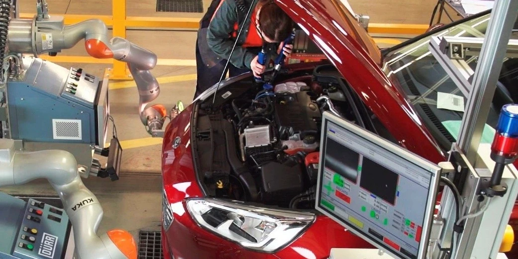 employee and robot working on a car