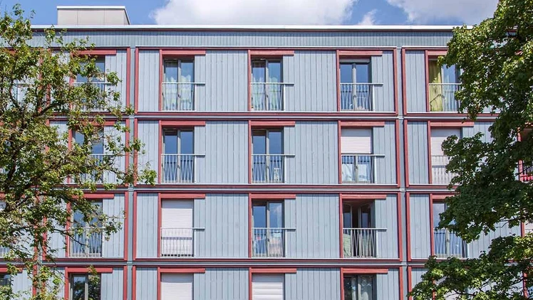 Timber construction facade behind trees.