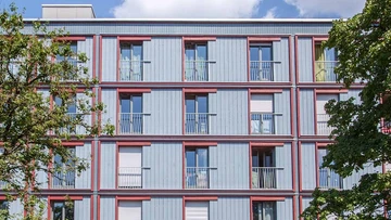 Timber construction facade behind trees.