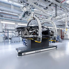 Anwendung für die Automobilindustrie. Das mit dem höhenverstellbaren Träger synchronisierte fahrerlose Transportsystem (FTS) transportiert die Karosse.