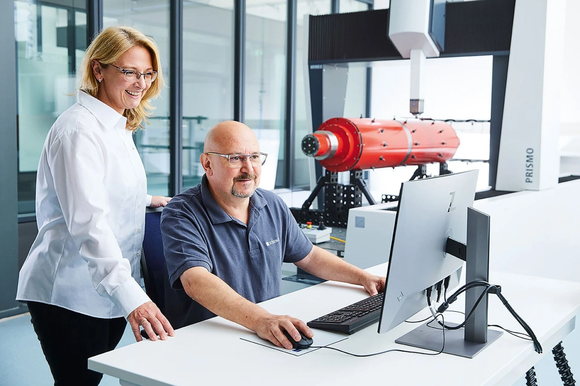 Colleagues next to a computer and a coordinate measuring machine