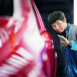 Employee checking the paint finish of a car