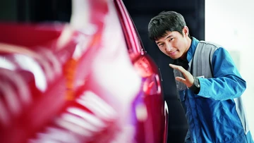 Employee checking the paint finish of a car