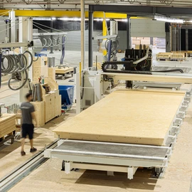 Automatisierte Fertigungslinie mit Holzplatten in einer Produktionshalle.