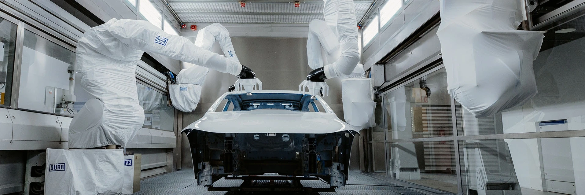 White-covered painting robots operating on a car body