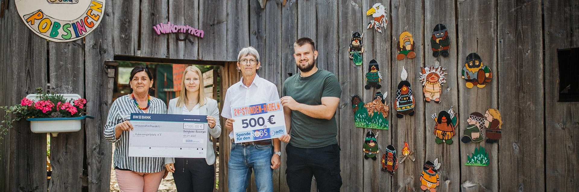 Dürr-Mitarbeiterin übergibt Spendenscheck an Mitarbeiter des Robinsonspielplatz