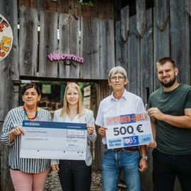 Dürr-Mitarbeiterin übergibt Spendenscheck an Mitarbeiter des Robinsonspielplatz