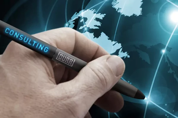 A hand with a glowing pen on which the Dürr Consulting logo is illuminated points to a glowing globe to show the worldwide activities of Dürr Consulting.